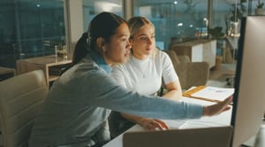 Two women discussing information on a computer screen